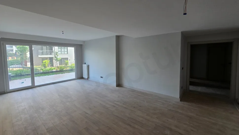 Просторная и светлая пустая гостиная с большими окнами и современным архитектурным дизайном.